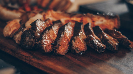 Sliced grilled meat on a cutting board with a sharp knife