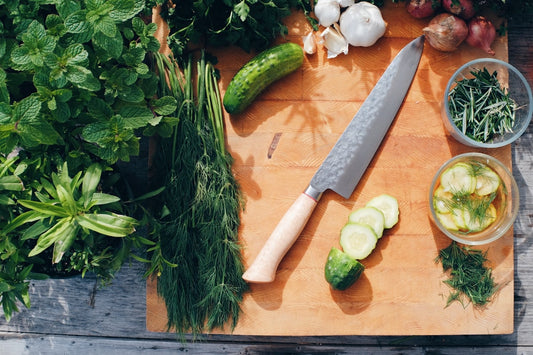 Gyuto Japanese chef knife on cutting board with sliced vegetables